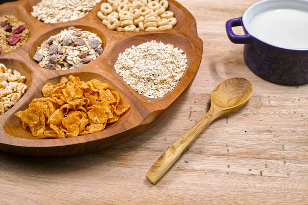 Wooden bowl with mixed breakfast cereals and blue bowl with fres
