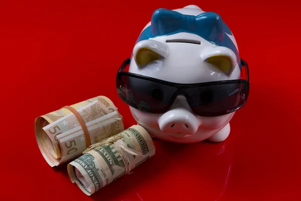 Piggy bank with black sunglasses and rolls cash