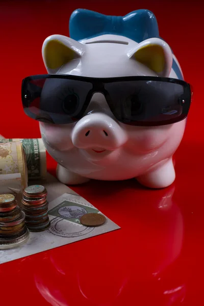 Piggy bank with black sunglasses and rolls cash