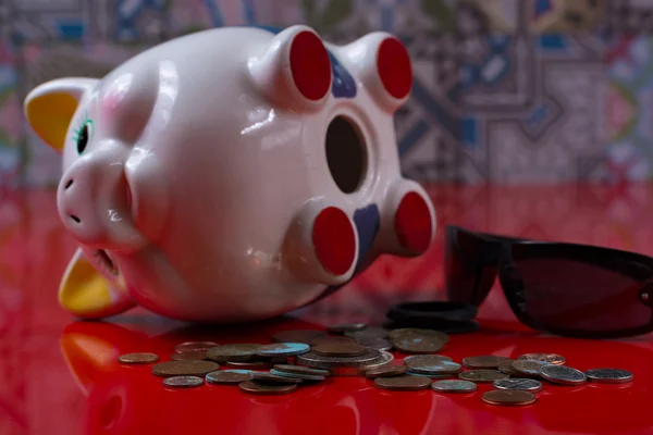 Opened piggy bank with black sunglasses and rolls cash