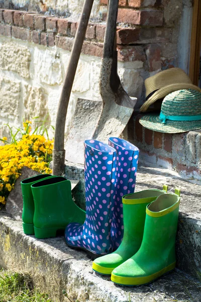 Garden equipment - rubber boots, shovels and straw hats in sunny day