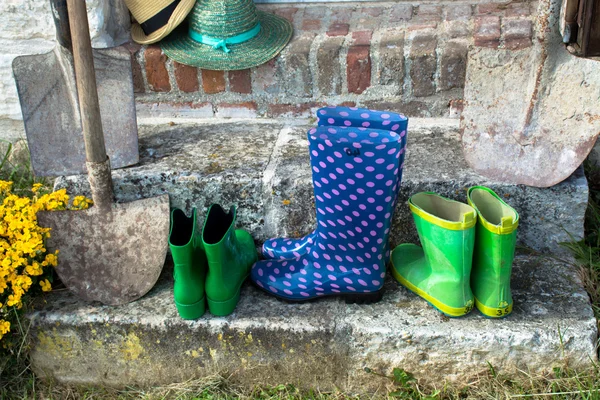 Garden equipment - rubber boots, schovels and srtaw hats in sunn