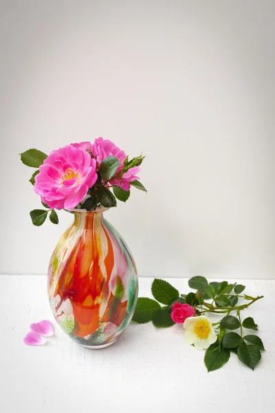 Small cololfrul glass vase with pink wild roses