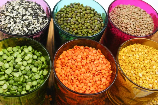 Multicolored clear glasses with various legumes ( green peas, red lentils, canadian lentils, indian lentils, black lentils, green lentils, green mung beans)