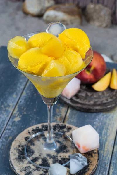 Fresh yellow peach ice-cream scoops in glass cone on the beach