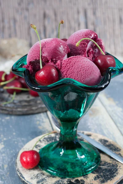 Fresh cherry ice-cream scoops in glass cone on the beach, summer
