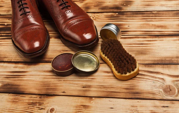 Shoe care. Shoe wax and brushes on wooden surface.