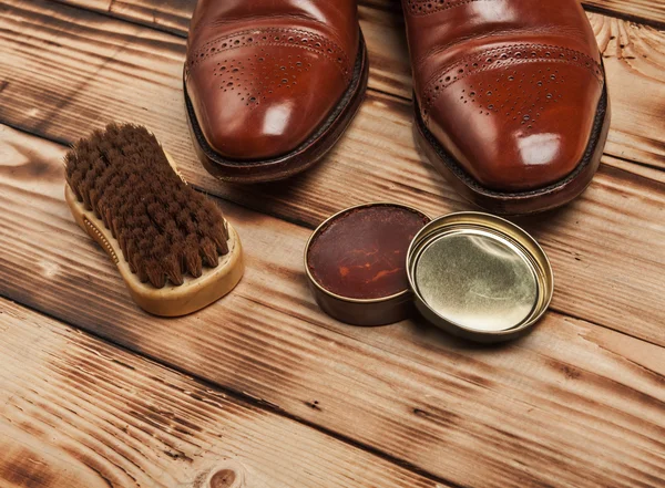 Shoe care. Shoe wax and brushes on wooden surface.