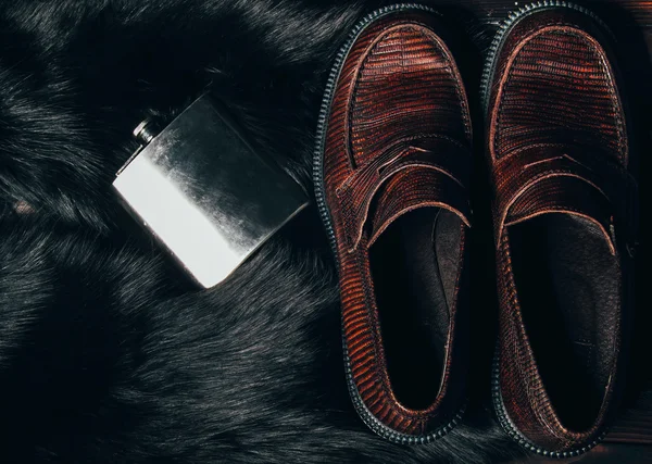 Mocasine (shoes) of snake skin and stainless flask on the fur. F