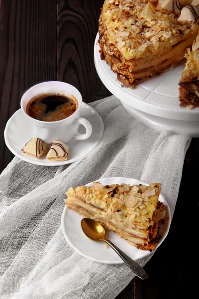 Piece of cake napoleon, puff on white plate, cup with coffe, can