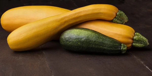 Two yellow big and medium  small green zucchini on wooden table.Family of zuccini.
