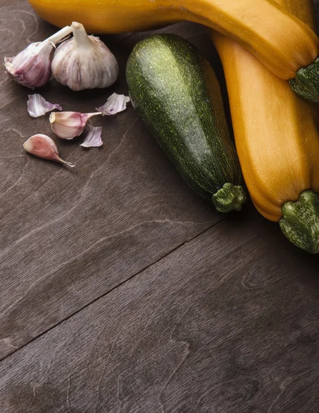 Two yellow big and medium  small green zucchini on wooden table. garlic,chiveFamily of zuccini.Vertical shot free space