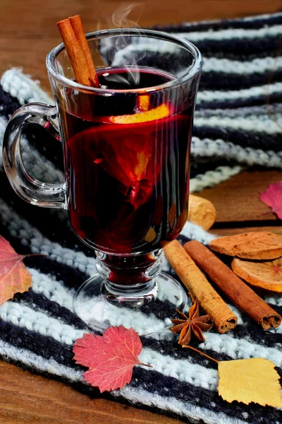 Hot Mulled wine with spices cinamon, star anise and dried lemon on knitted scarf .Fallen leaves. Autumn theme.Selective focus.Vertical shot