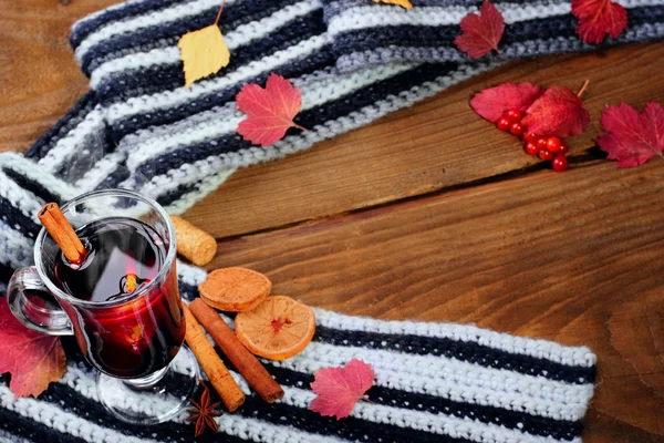 Hot Mulled wine with spices cinamon, star anise and dried lemon on knitted scarf .Fallen leaves. Autumn theme.Selective focus.Top view.Focus on glass with wine