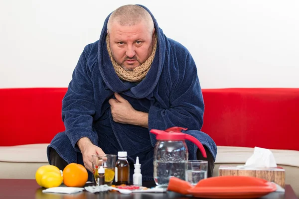 Sick man wearing pajama suffering cold and winter flu virus having medicine