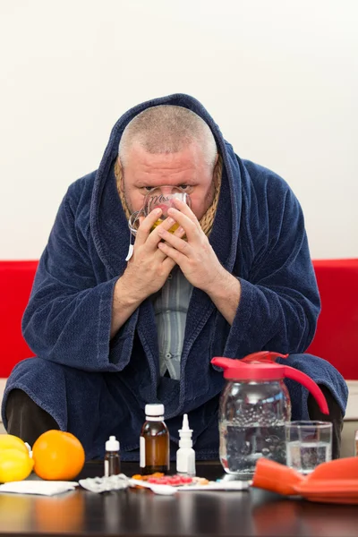 Sick man wearing pajama suffering cold and winter flu virus having medicine