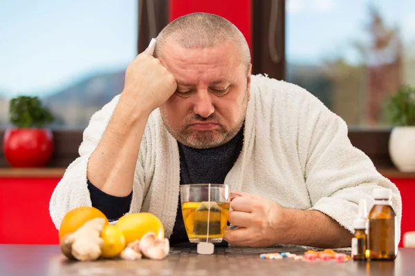 Sick man suffering cold and winter flu virus drinking tea