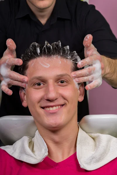 Portrait of male client getting his hair washed at salon