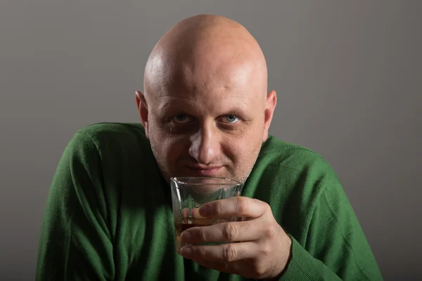 Bald headed man drinking whiskey