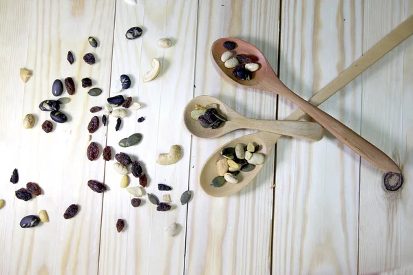 Organic mixed nuts with wood spoon on wood background