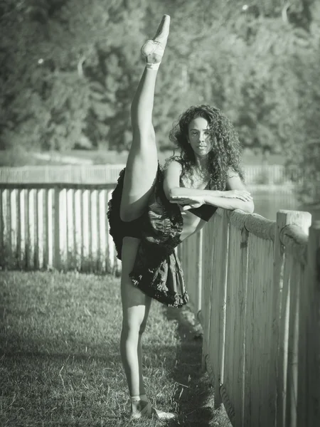 Latin dancer with raised leg and arms crossed, monochrome