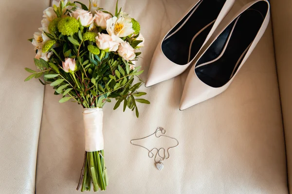 Close-up of bridal bouquet of roses, wedding flowers for the ceremony on the bed in a hotel room with white shoes