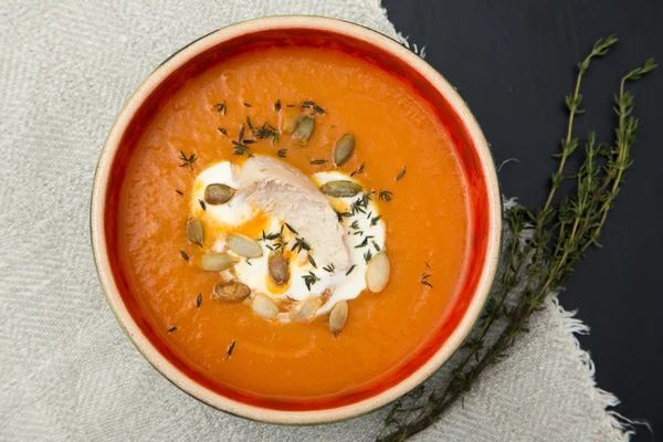 Pumpkin cream soup with chicken fillet, thyme and pumpkin seeds.