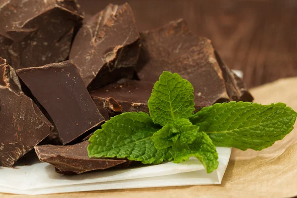 Dark chocolate with cacao and mint leaf on dark wooden table