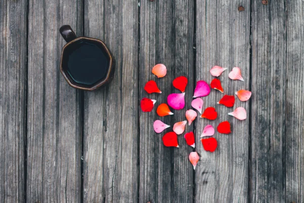 Cup of coffee and heart lined with petals