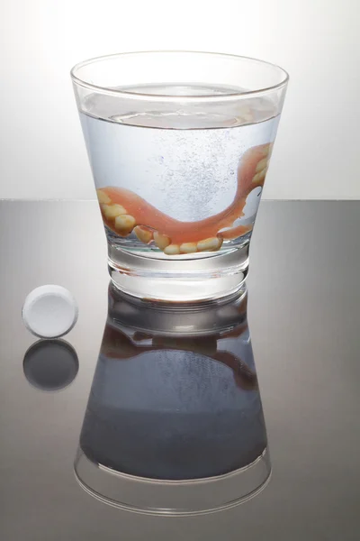 Cleaning a denture in a glass with water.Proper of hygiene.