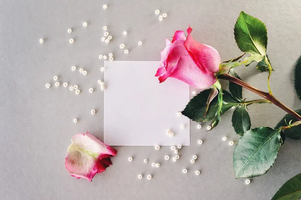 Pink rose and white pearls on a white sheet of paper