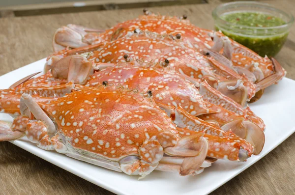 Steamed crabs in dish on wood background