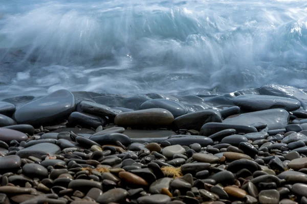 Light surf on the sea shore, stones and water closeu