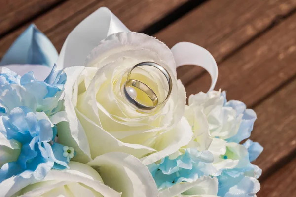 Silver wedding rings are on petals of artificial rose