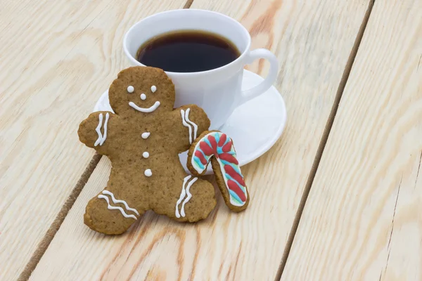 Homemade gingerbread cookie man and cup of coffee on wooden table
