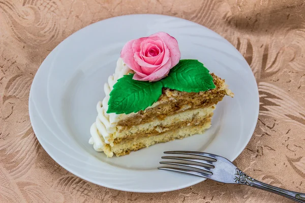 Piece of sponge cake that is decorated with sugar rose
