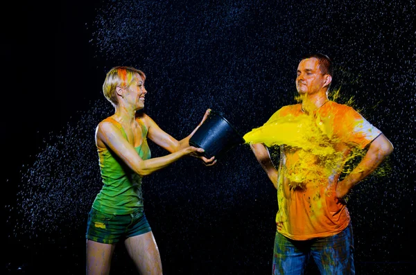 Woman pours a bucket of paint Man