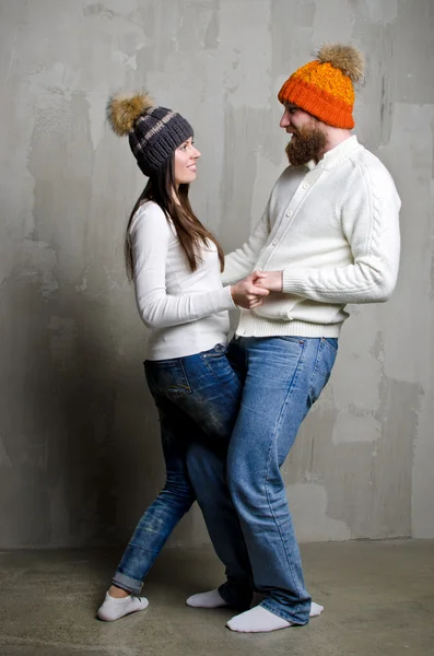 A man and a woman in a knitted hat with pom-poms