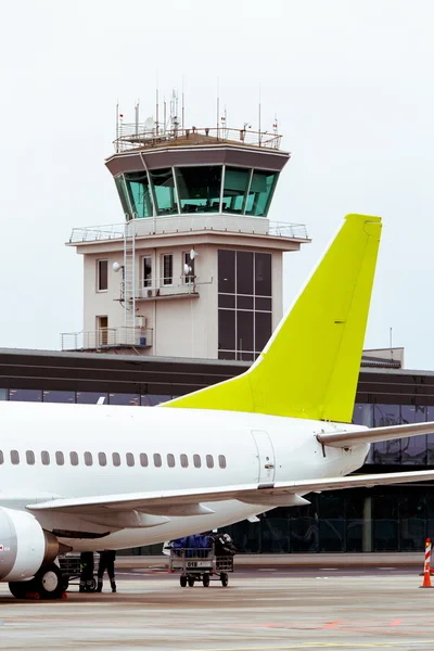 Air control tower at airport, with plane tail on foreground