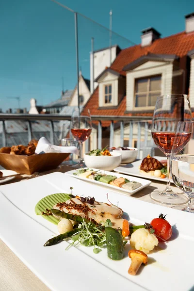Table for two with food at rooftop restaurant, grilled fish  garnish.