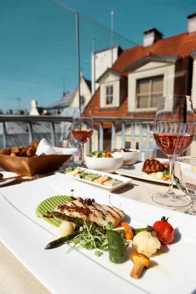 Table for two with food at rooftop restaurant, grilled fish  garnish.