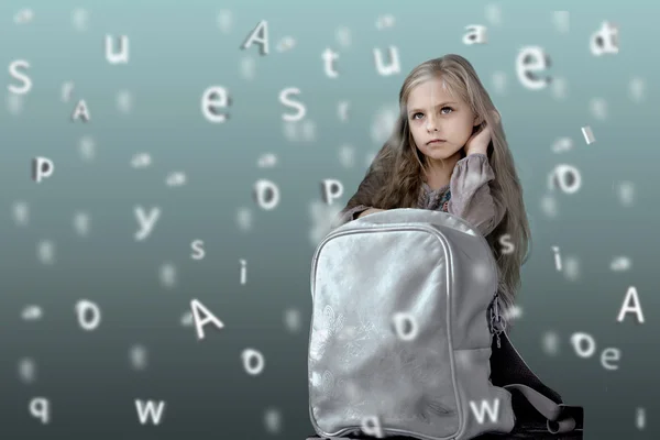 Children. alphabet. cute little girl with school backpack on the background of the emerging letters