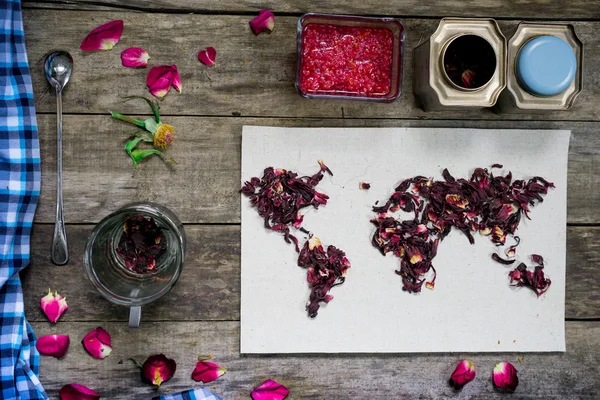 Map of the world, lined with tea leaves on old paper. Eurasia, America, Australia, Africa. vintage. hibiscus tea, cup, a towel, raspberry jam on rustic wooden table. top view. flat lay