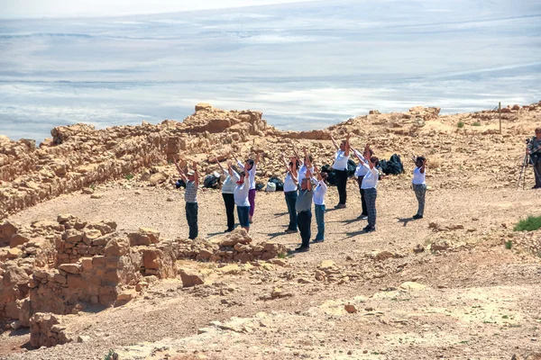 A group of people raises his arms to the sun at Masada\'s ruins, Israel