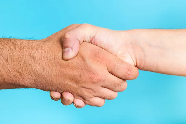Cooperation agreement concept. Shaking hands on blue background.