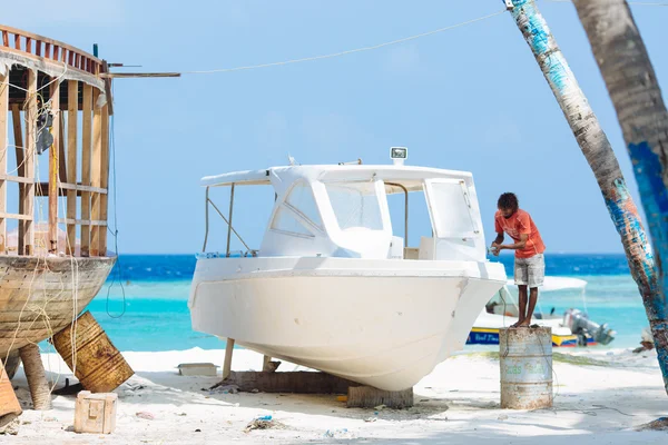 MAAFUSHI, MALDIVES - JANUARY 5, 2013: Craftsman repairs a speedboat to be ready for a new tourist season.