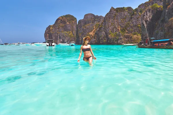 Young woman walks in turquoise clear waters of the Maya bay lagoon