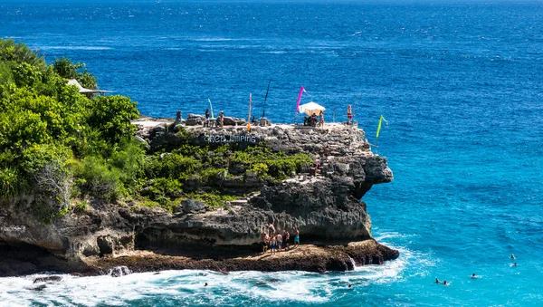 Cliff jumping area. People jumping to the water and relaxing on the beach