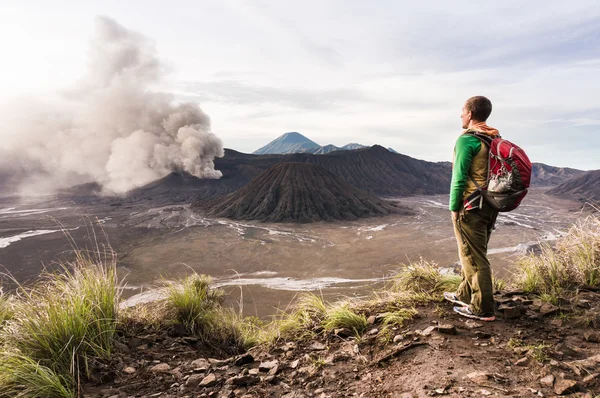 Man on the hill is looking on Bromo volcano eruption. East Java, Indonesia