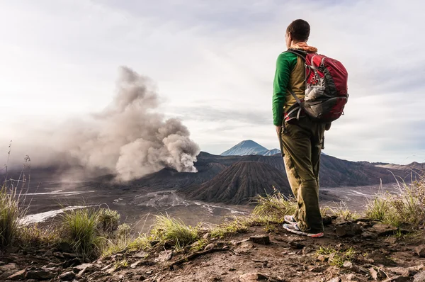 Man on the hill is looking on Bromo volcano eruption. East Java, Indonesia